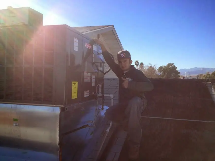 HVAC technician performing Heat Pump Repair on a rooftop unit in Seven Oaks
